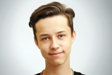 Genç gülümseyen sevimli genç gri arka plan üzerinde portresi