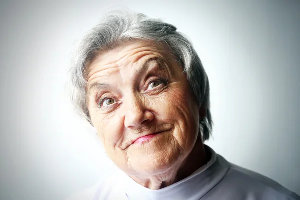 Olhando retrato de mulher velha em um fundo cinza — Fotografia de Stock