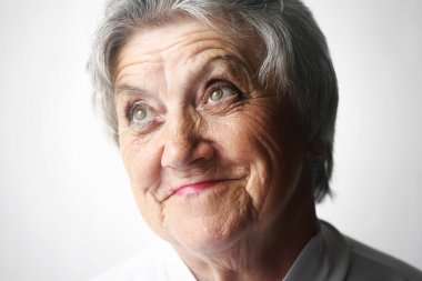 Yaşlı kadın portre gri bir arka plan üzerinde seyir