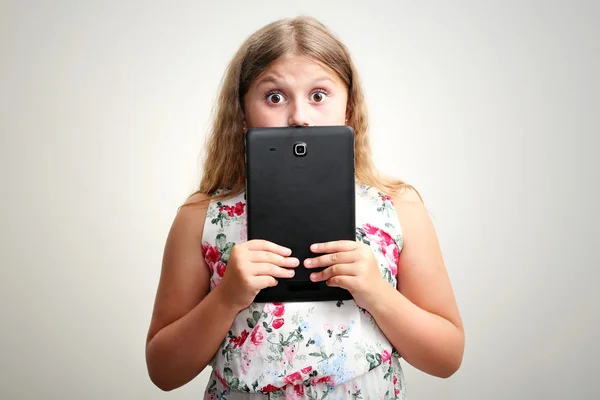 Маленькая девочка улыбается и удивляется планшетный компьютер — стоковое фото