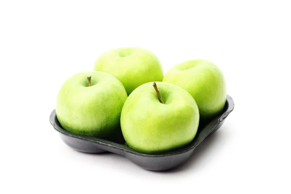 Groene appels op de zwarte kunststof plaat geïsoleerd op wit — Stockfoto