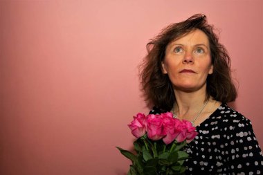 Sevgililer Günü için gül alan mutlu bir partneri yakalamak, çevresindeki pembe ve romantik arka plana sahip..