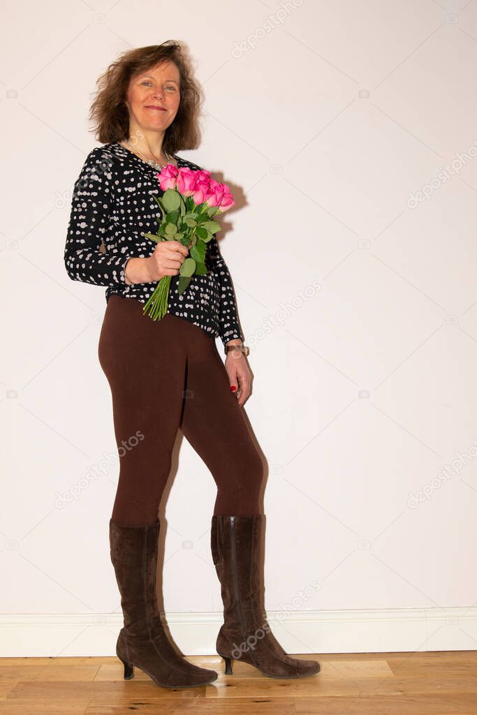 Capturing a happy partner who has received roses for Valentine`s Day, with an ambient pink and romantic background.