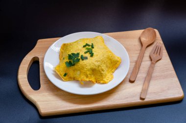 Siyah arkaplanda beyaz tabakta omlet..