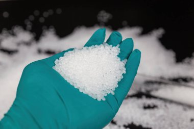 Siyah arkaplanda beyaz plastik boncuklar, polimer reçine, polimer palet, petrokimyasal fabrikalardan alınmış ürünler. granüller polimer,