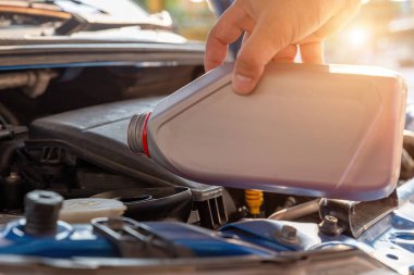 Makine yağını değiştir. Tamirci, yeni yağları değiştirip döküyor. Tamir otomobili. Taze yağ doldur. Motor yağı dolum noktası..