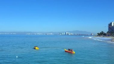 Porto Vallarta 'daki Playa De Los Muertos plajında turistler için muz teknesi ve çeşitli eğlenceli su sporları aktiviteleri