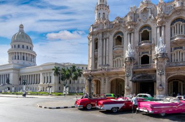 Happy tourists enjoying a taxi ride in famous colorful vintage Cuban taxis along Paseo del Prado, El Capitolio and Havana historic city center during their vacation time