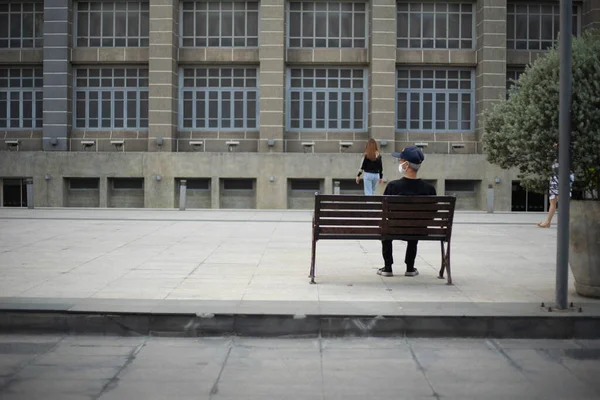 asian old man wear mask sitting alone watch people on city