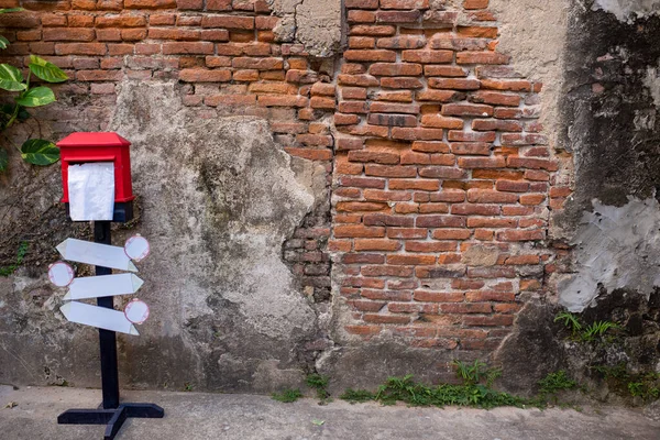 Harap olmuş duvarın önündeki kırmızı posta kutusu.