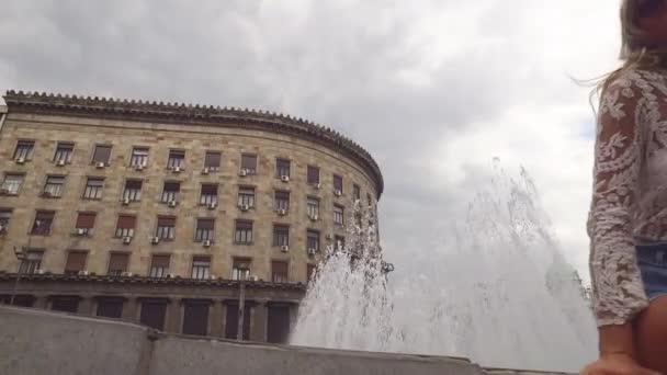 Nuori viehättävä nainen istuu suihkulähteellä keskustan aukiolla Belgradin Serbiassa — kuvapankkivideo