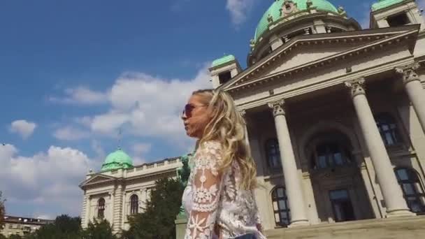 Jonge vrouw loopt voor Servisch parlementsgebouw in Belgrado — Stockvideo