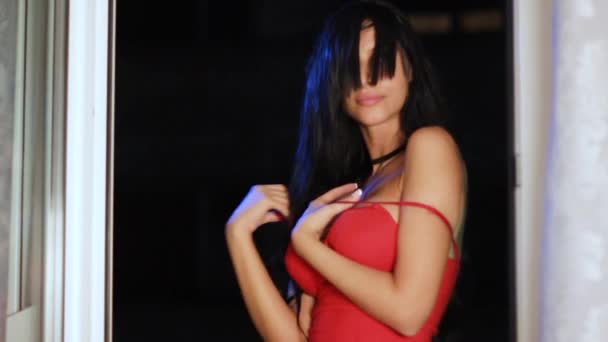 Sexy Feminino em um vestido vermelho posando sedutor para câmera enquanto joga com correias — Vídeo de Stock