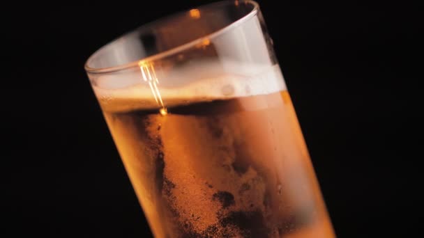 Cerveja leve fria no vidro, girando perto no fundo preto — Vídeo de Stock