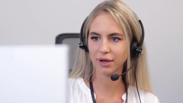 Ung kvinna med headset arbetar på callcenter och pratar med kunden — Stockvideo