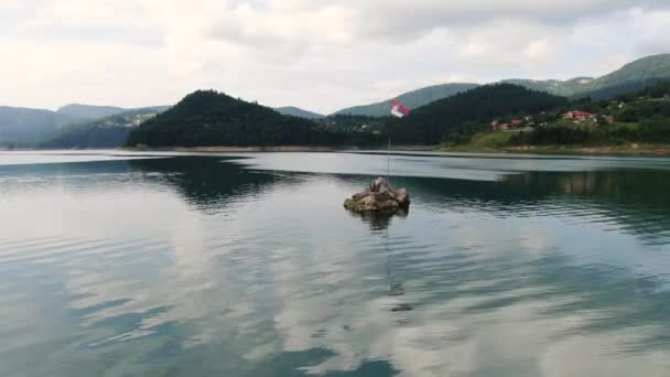 Vista aérea, bandeira nacional sérvia na pequena ilhota em Zaovine Lake, Tara Mountain — Vídeo de Stock