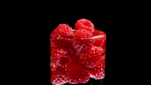 Framboises rouges mûres en verre d'eau tournent, fond noir isolé — Video