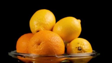 Cam Tabakta Yığılmış Limonlar ve Portakallar Döner, Siyah Arkaplan