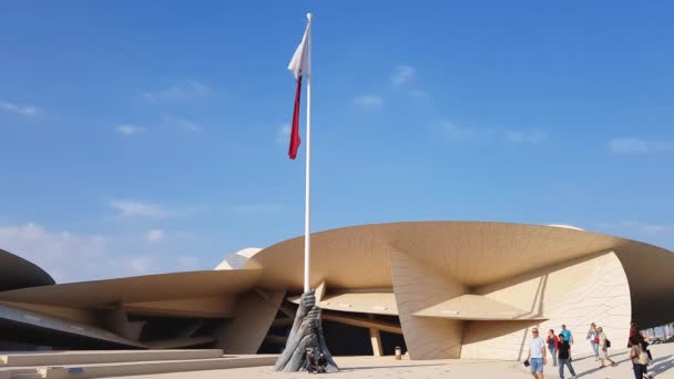 Doha, Außenseite des Nationalmuseums, Katars Nationalflagge und Menschen am sonnigen Tag — Stockvideo