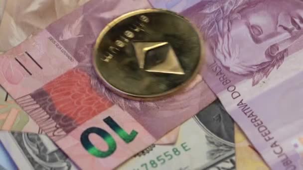 Het laten vallen van Ethereum ETH en Bitcoin gouden munten op Braziliaanse Reals en dollars — Stockvideo