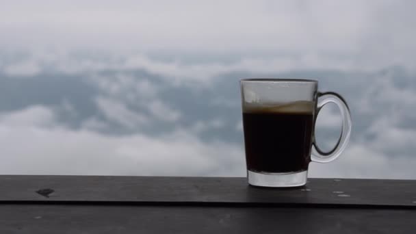 Großaufnahme von heißem Kaffeegetränk in transparenter Tasse mit Wolken im Rücken, Detail — Stockvideo