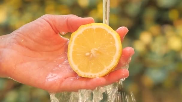 Limón en la mano bajo agua corriente — Vídeo de stock