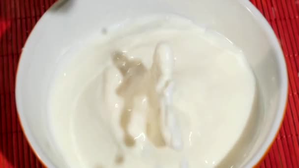 Two biscuits falling into a bowl full of fresh milk — Stock Video