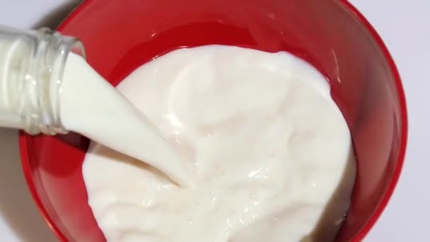 Verter leche en un tazón rojo — Vídeos de Stock