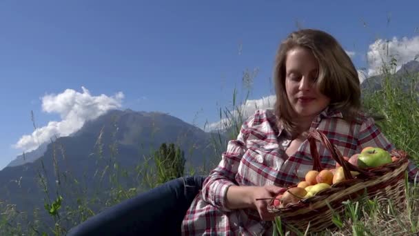 Красивая крестьянка с корзиной фруктов над альпийской панорамой — стоковое видео