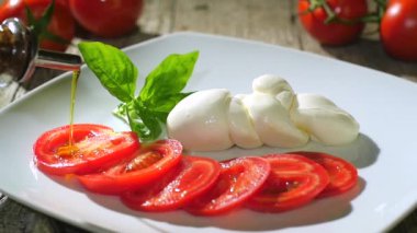 Zeytin yağı üzerinde caprese salatası dökme.