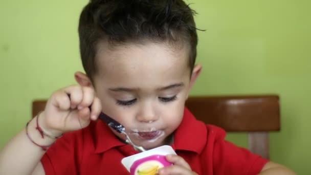 Молодий хлопчик їсть йогурт вдома — стокове відео