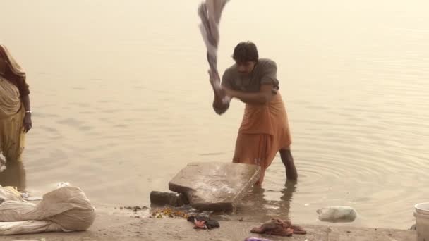 Varanasi, Indien, Mann wäscht Kleidung im heiligen Ganges River — Stockvideo