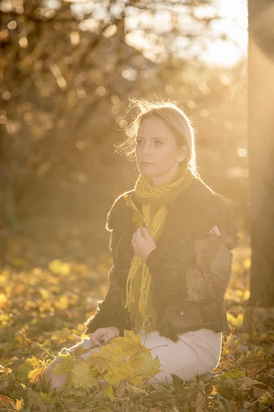 Vrouw met najaar bladeren in de zonsondergang — Stockfoto