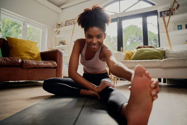 Africano mulher saudável feliz em sportswear fazendo exercício de alongamento em casa no tapete de fitness durante o bloqueio do vírus corona — Fotografia de Stock