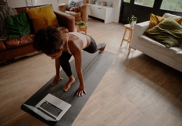 Високий кут зору жінки дивитися відео на ноутбук під час вправ на йога мат вдома — стокове фото