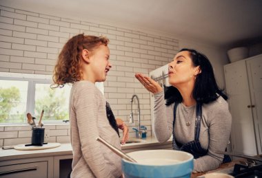 Oyuncu anne ve kız evdeki modern mutfakta unla oynarken yemek hazırlıyorlar.