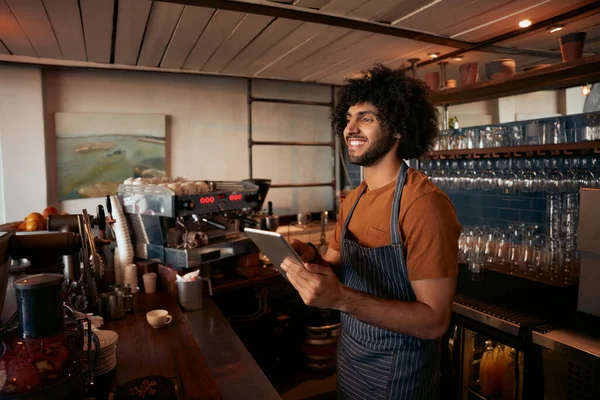 Sorridente imprenditore maschile nella sua caffetteria tenendo scheda digitale — Foto Stock