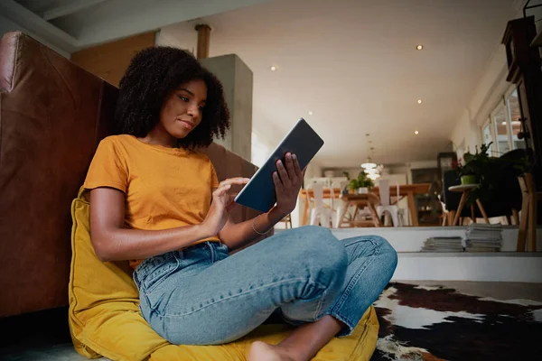 Genç bir kadın dijital tabletle evde oturuyor. — Stok fotoğraf
