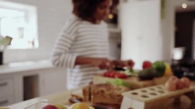 Genç bir Afrikalı kadının taze sebzeleri bıçakla keserken görüntüsünü büyüt. Mutfakta sağlıklı salata hazırlıyor.