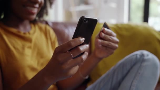 Νεαρό κορίτσι που κάθεται στο σπίτι εισάγει τα στοιχεία της πιστωτικής της κάρτας για μια online παραγγελία στο κινητό τηλέφωνο — Αρχείο Βίντεο