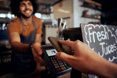 Kafe 'de garsonun elinde makineyle akıllı telefon kullanarak ulaşılamaz bir ödeme yapan genç bir kadın var.
