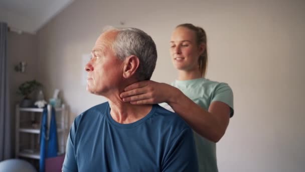 Schuss einer jungen Physiotherapeutin, die einem älteren Mann in der Klinik den Hals manipuliert — Stockvideo