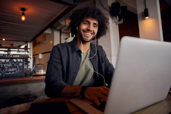 Glücklicher junger Mann schaut sich Video online auf Laptop mit Kopfhörer im Café an — Stockfoto