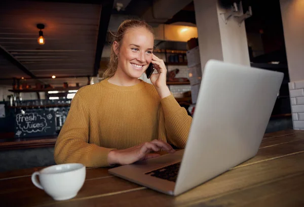 Πορτρέτο της χαμογελαστή νεαρή γυναίκα των επιχειρήσεων μιλάμε πάνω από το smartphone και τη χρήση φορητού υπολογιστή στο καφέ — Φωτογραφία Αρχείου