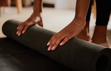 Genç kadın ellerinin yoga minderini yere yuvarlamasının yakın çekimi.