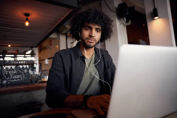 Droevige jonge man kijken video op laptop met oortjes in modern cafe — Stockfoto