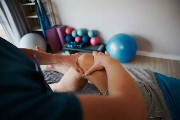 Close-up de jovem fisioterapeuta do sexo feminino ajudando o homem com exercício no joelho — Fotografia de Stock