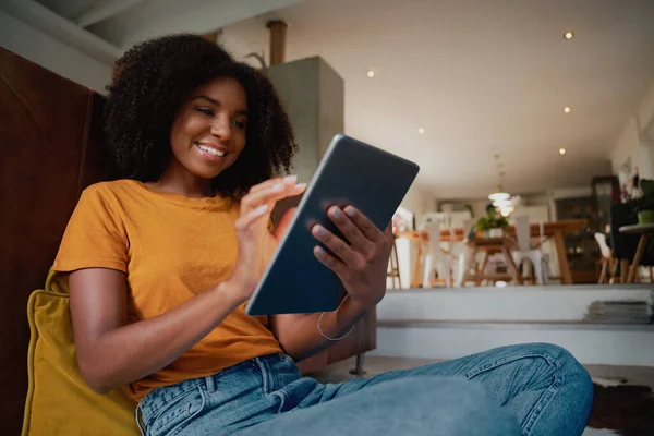 Vrolijke Afrikaanse vrouw zit thuis op de vloer met digitale tablet thuis ontspannen — Stockfoto