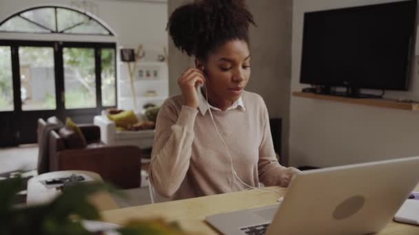 Snímek mladé ženy pracující on-line pomocí notebooku doma mluvit na sluchátka a psaní poznámek do deníku — Stock video