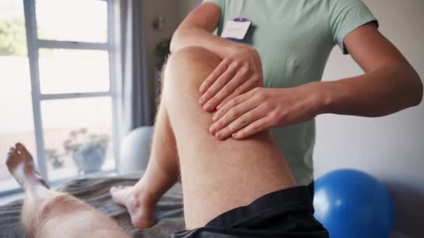 Beskuren bild av en kvinnlig terapeut som behandlar en manlig patients skadade knä — Stockvideo